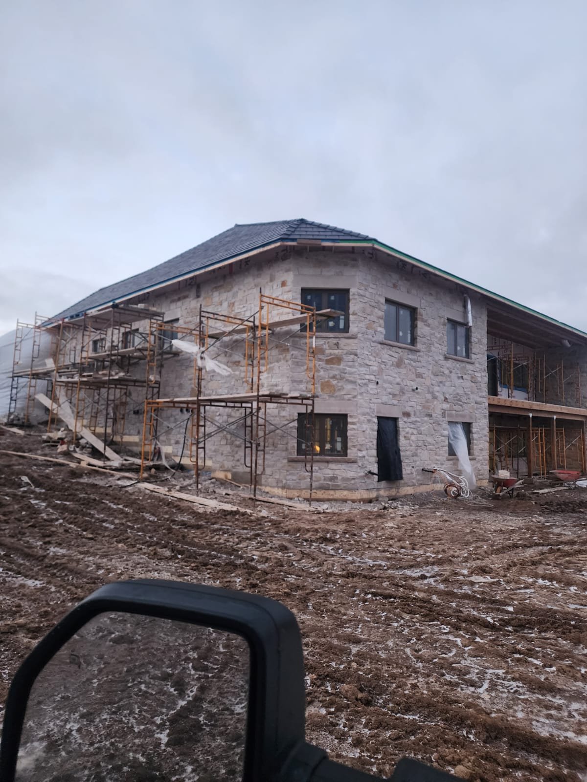 Large stone-clad residence under construction with scaffolding
