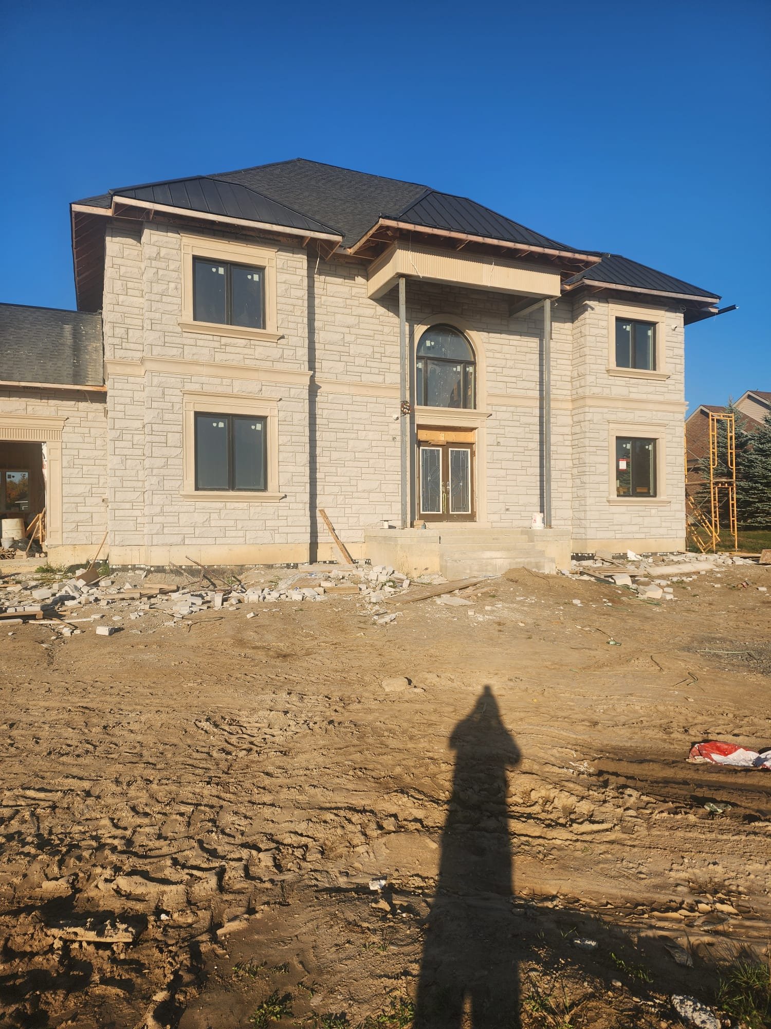 Near-complete pale stone custom home with dark-framed windows
