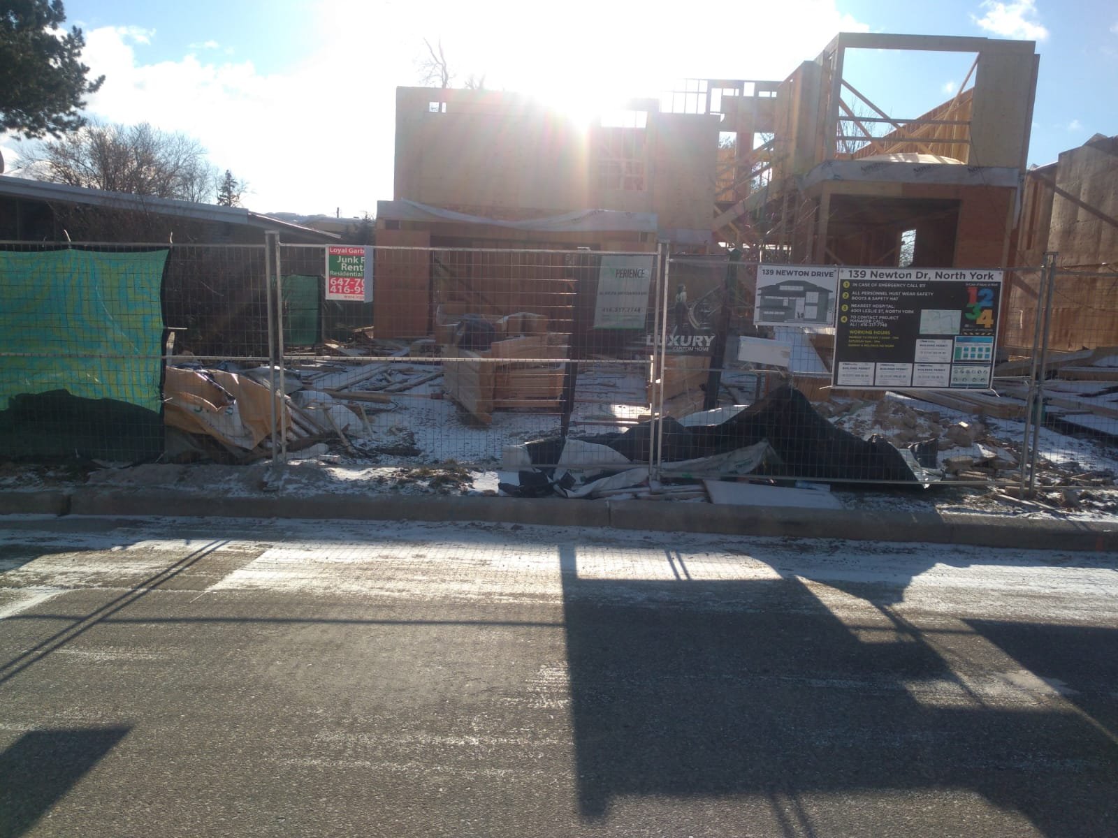 Street-front residential framing stage with temporary construction signage